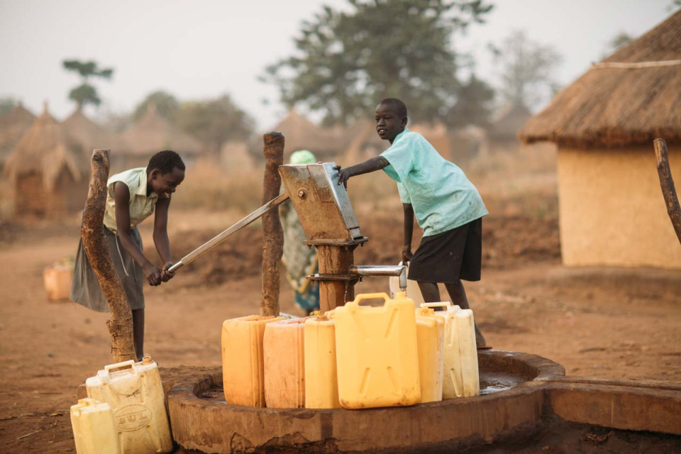 Enfants actionnant la pompe manuelle d'un puit en Ouganda